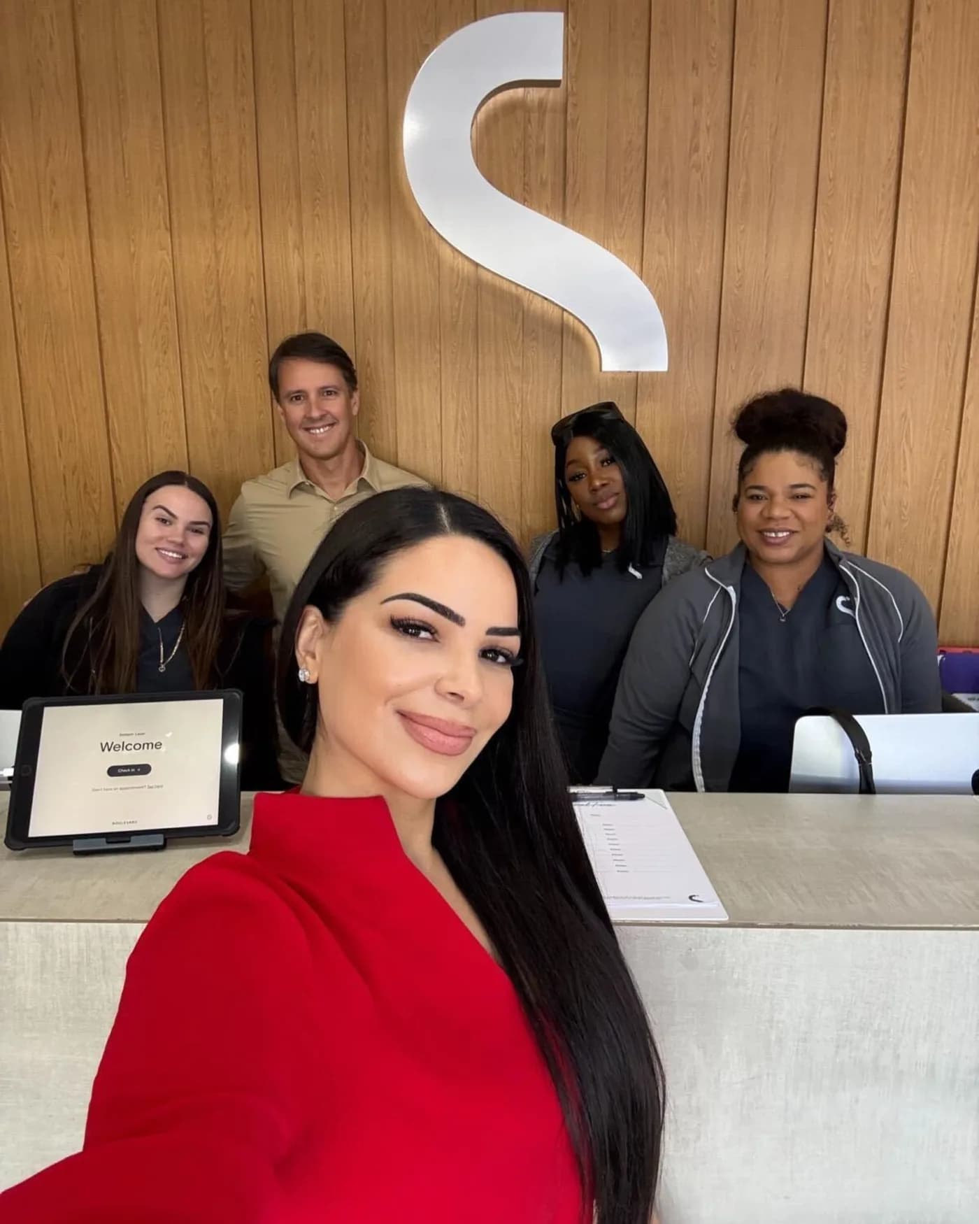 Semper Laser team members gathered at a studio front desk